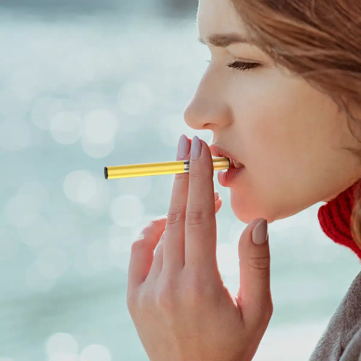 Woman vaping a Mosmo Stik disposable vape in Love 69 flavor outdoors